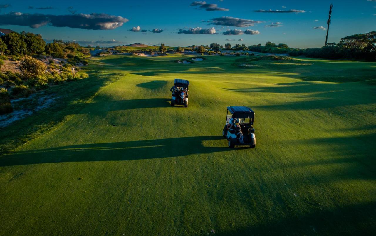 Pullman Magenta Shores Resort Entrance Buitenkant foto Golf carts on the green